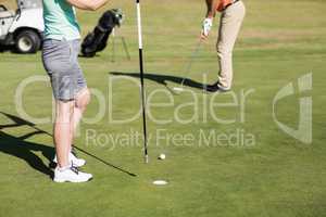 Low section of couple playing golf