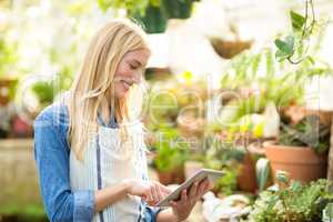 Female gardener using digital tablet at greenhouse