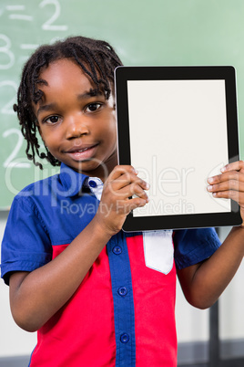 Smiling boy holding digital tablet in classroom