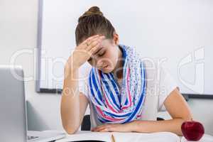 Stressed teacher suffering from headache in classroom