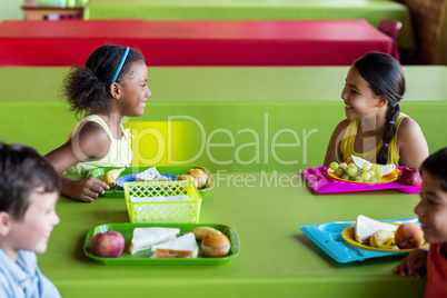 Happy schoolchildren having breakfast