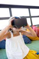 Girl holding virtual reality headset while sitting in library