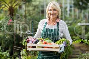 Female gardener holding vegetables crate