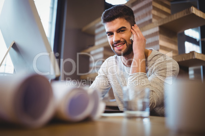 Confident businessman talking on cellphone at computer desk