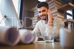 Confident businessman talking on cellphone at computer desk