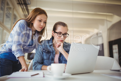 Businesswoman working on laptop with colleague in creative offic
