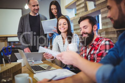 Businessman giving documents to coworker during meeting