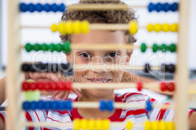 Cute boy playing with abacus in classroom