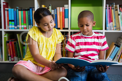 Elementary students reading book at library in school