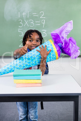 Boy holding gift at table in classroom