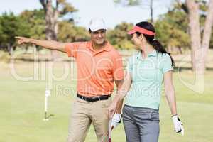 Cheerful golfer man pointing while standing by woman