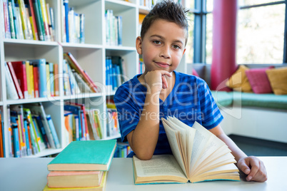 Boy reading book at table in school library