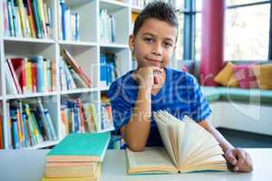 Boy reading book at table in school library