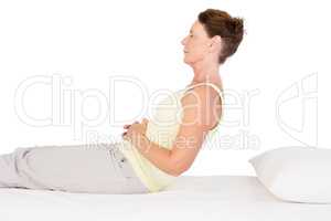 Side view of mature woman exercising on bed