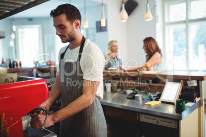Confident barista using espresso maker at coffee shop