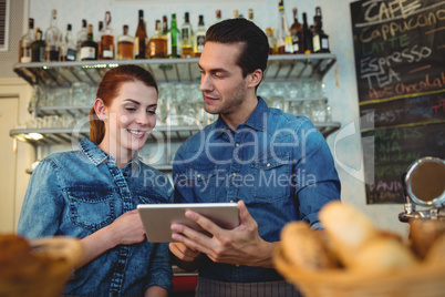 Young baristas with digital tablet at cafe