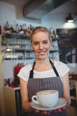 Portrait of confident waitress serving coffee at shop