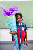 Boy holding gift against board in classroom