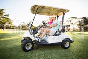 Golfer couple sitting in golf buggy