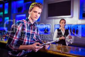 Portrait of man using digital tablet with bartender working