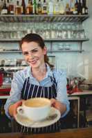 Portrait of confident barista serving coffee at cafeteria