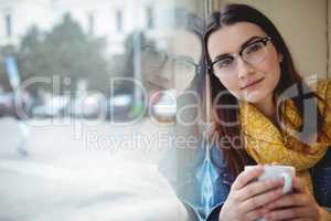 Portrait of beautiful woman sitting by window at cafe