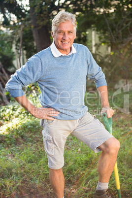 Portrait of happy gardener with tool standing at garden