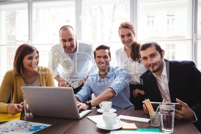 Smiling business people with laptop in meeting room
