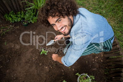 Smiling gardener planting outside greenhouse