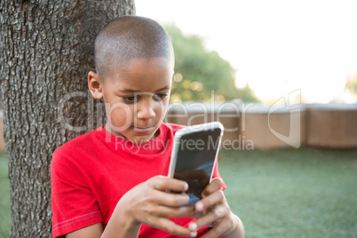 Elementary boy using mobile phone at park