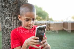 Elementary boy using mobile phone at park