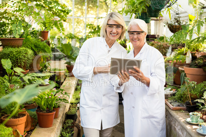 Female colleagues smiling while using digital tablet