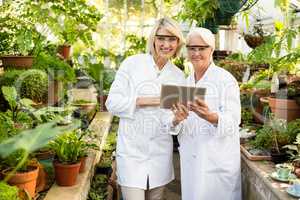 Female colleagues smiling while using digital tablet