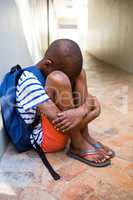 Sad boy sitting on corridor in school