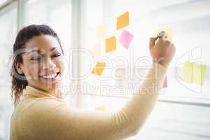 Portrait of happy businesswoman writing on adhesive notes in off