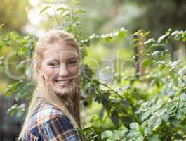 Happy female gardener standing by plants