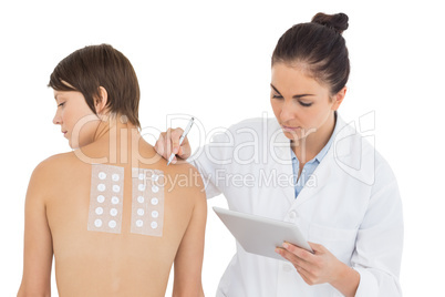 Doctor examining woman while holding digital tablet