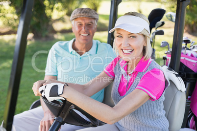 Smiling mature couple sitting in golf buggy