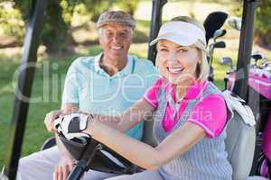 Smiling mature couple sitting in golf buggy