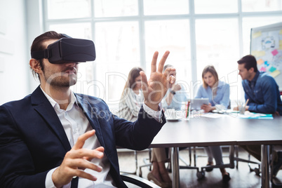 Businessman using virtual reality simulator against colleagues