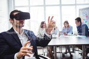 Businessman using virtual reality simulator against colleagues