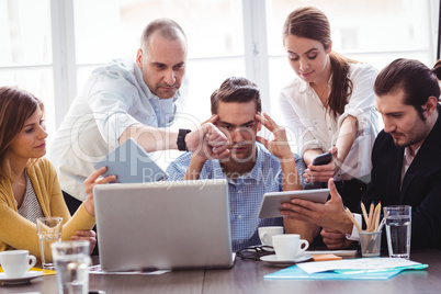 Irritated businessman in between coworkers showing technologies