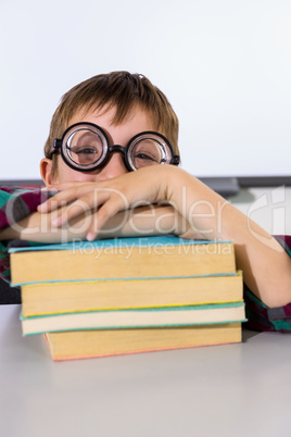 Boy leaning on books at table in classroom