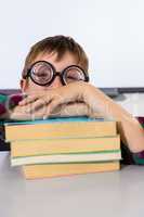 Boy leaning on books at table in classroom