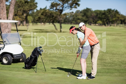 Side view of man teaching woman to play golf