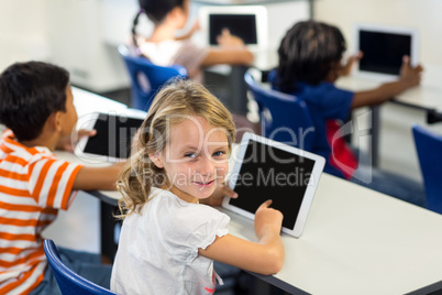 Schoolgirl with classmates using digital tablet