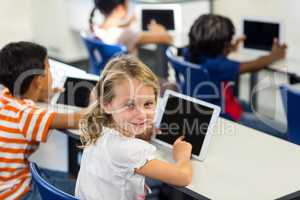 Schoolgirl with classmates using digital tablet