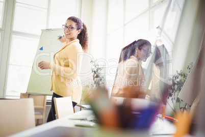 Businesswoman giving presentation on whiteboard in creative offi