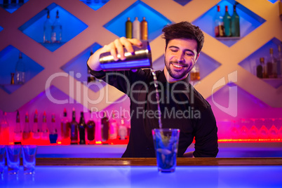 Barkeeper pouring cocktail in glass at counter
