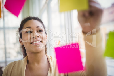 Young businesswoman smiling while writing on adhesive notes